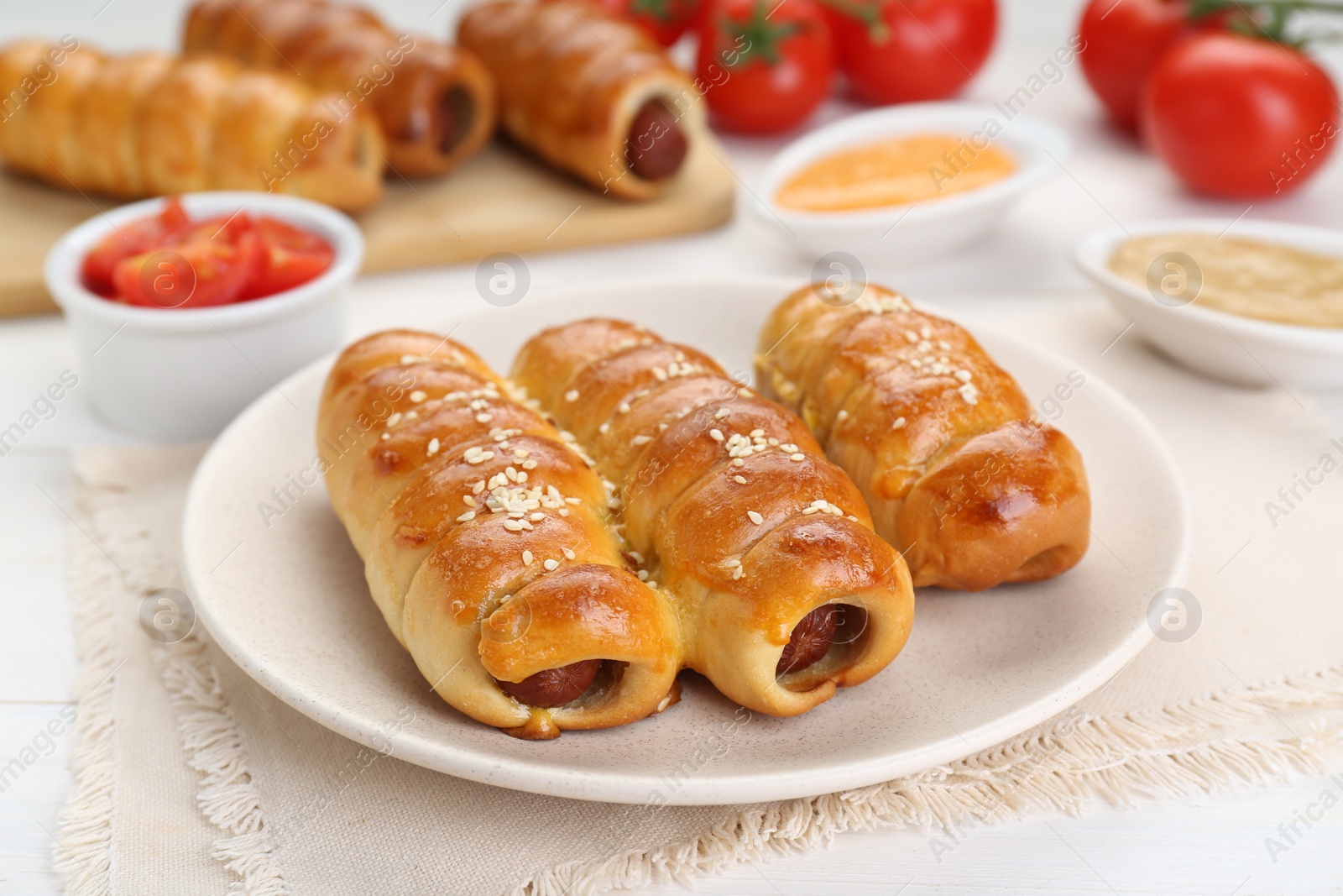 Photo of Delicious sausage rolls and ingredients on white wooden table