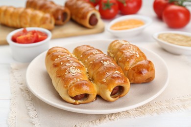 Delicious sausage rolls and ingredients on white wooden table