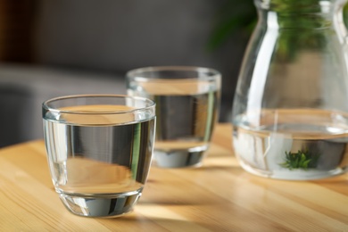 Photo of Glass of water on wooden table indoors, space for text. Refreshing drink