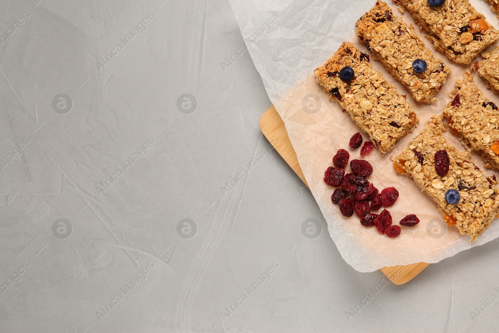 Photo of Tasty granola bars and dried cherries on light gray table, top view. Space for text