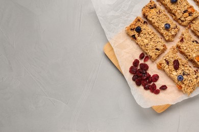 Photo of Tasty granola bars and dried cherries on light gray table, top view. Space for text