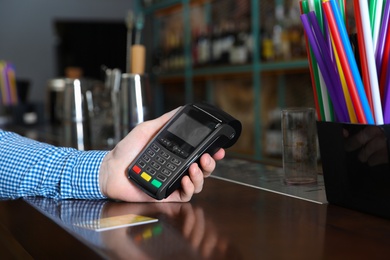 Photo of Man using credit card machine for non cash payment in cafe, closeup. Space for text