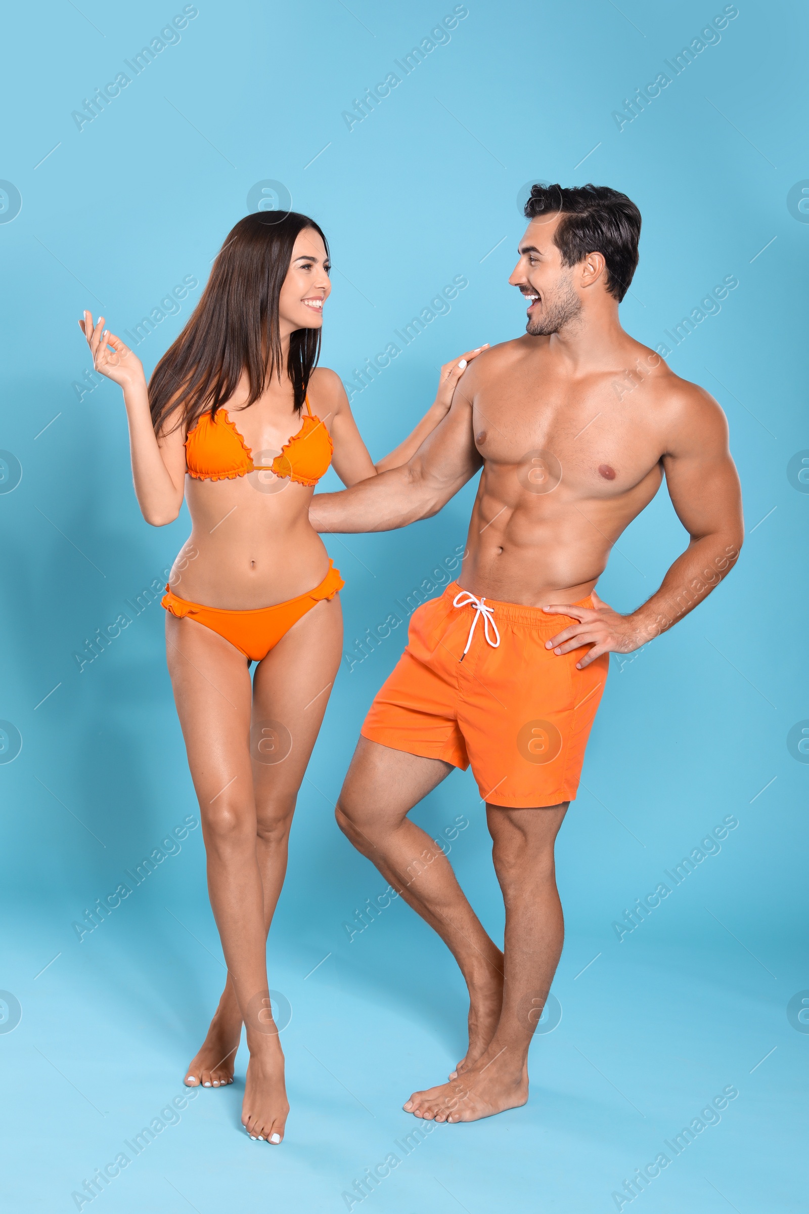 Photo of Young attractive couple in beachwear on blue background