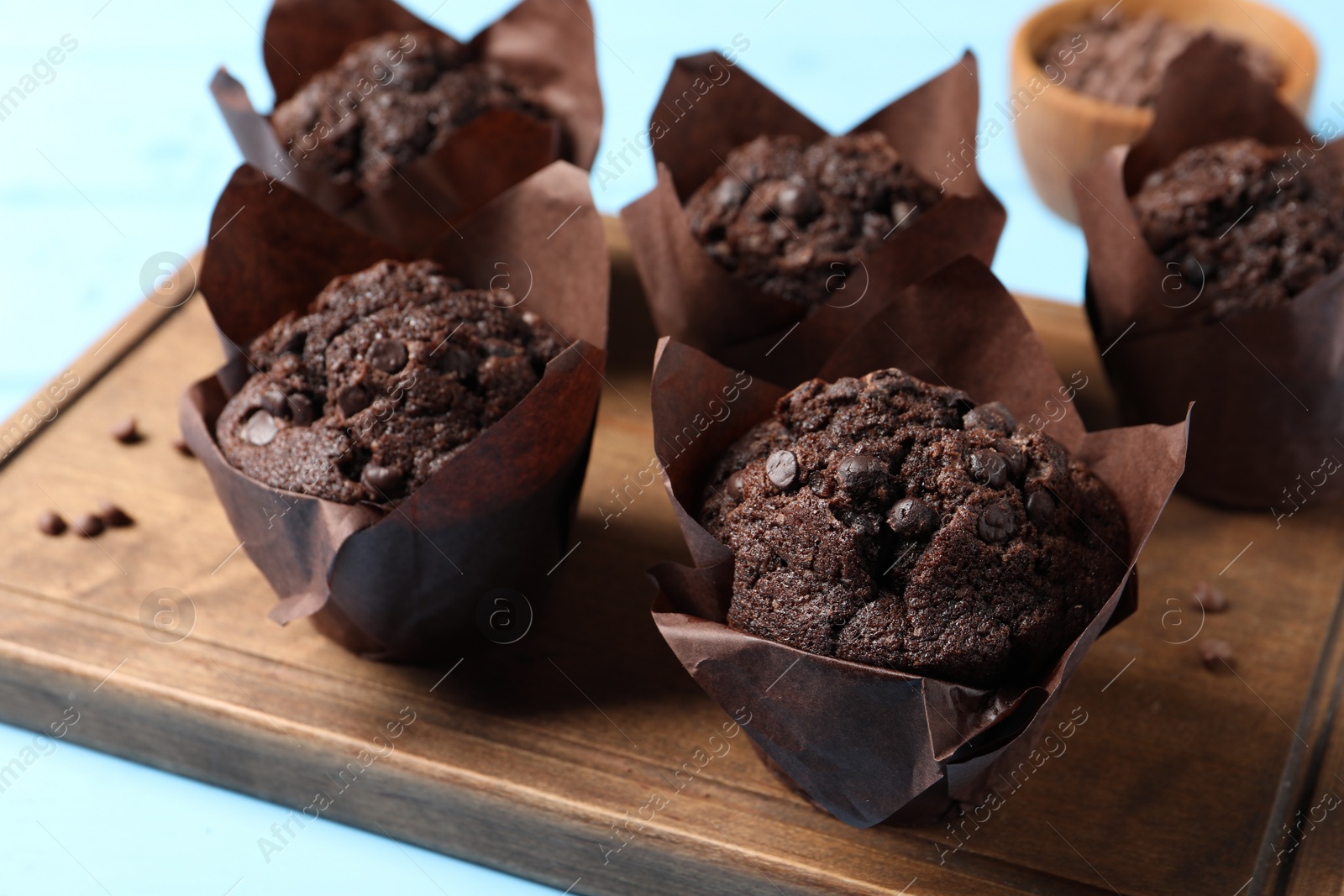 Photo of Tasty chocolate muffins on light blue table, closeup