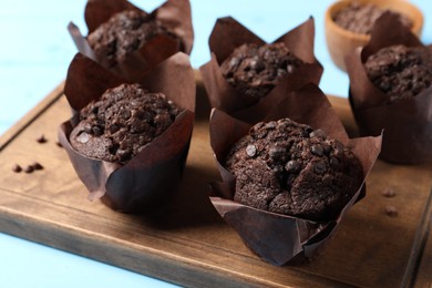 Photo of Tasty chocolate muffins on light blue table, closeup