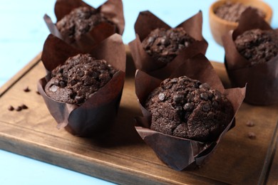 Tasty chocolate muffins on light blue table, closeup