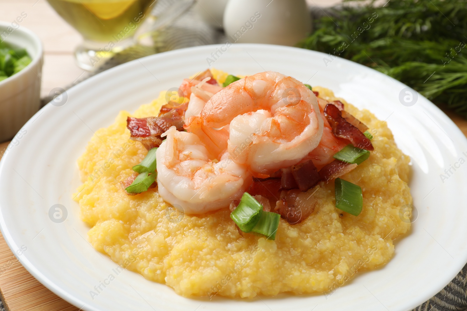 Photo of Plate with fresh tasty shrimps, bacon, grits and green onion on table, closeup