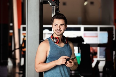Photo of Young man with headphones and mobile device at gym