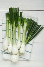 Whole green spring onions on white wooden table, flat lay