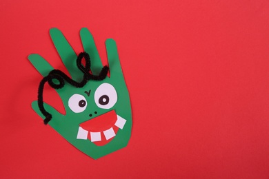 Photo of Funny green hand shaped monster on red background, top view with space for text. Halloween decoration