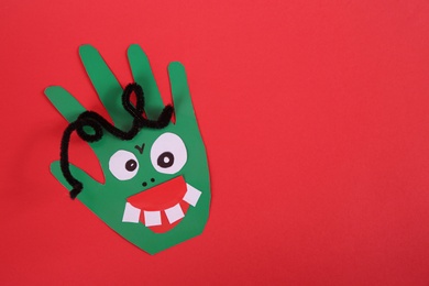 Funny green hand shaped monster on red background, top view with space for text. Halloween decoration