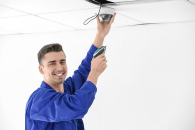 Photo of Technician installing CCTV camera on ceiling indoors