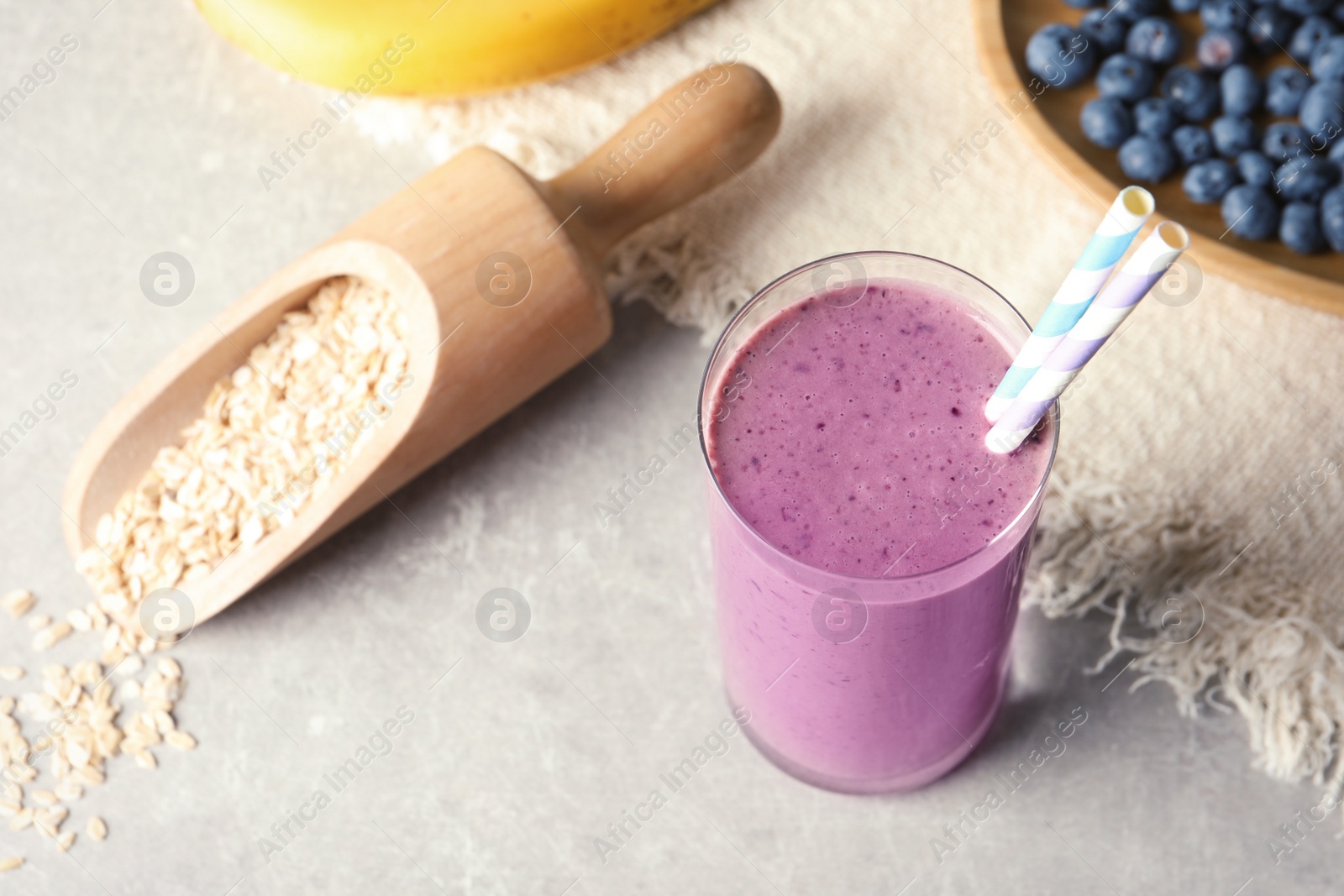 Photo of Glass with blueberry smoothie on grey table