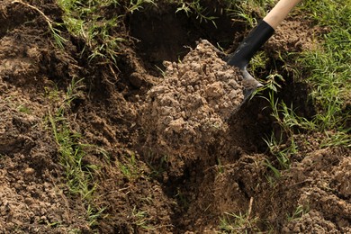 Photo of Digging soil with shovel outdoors, closeup. Gardening tool