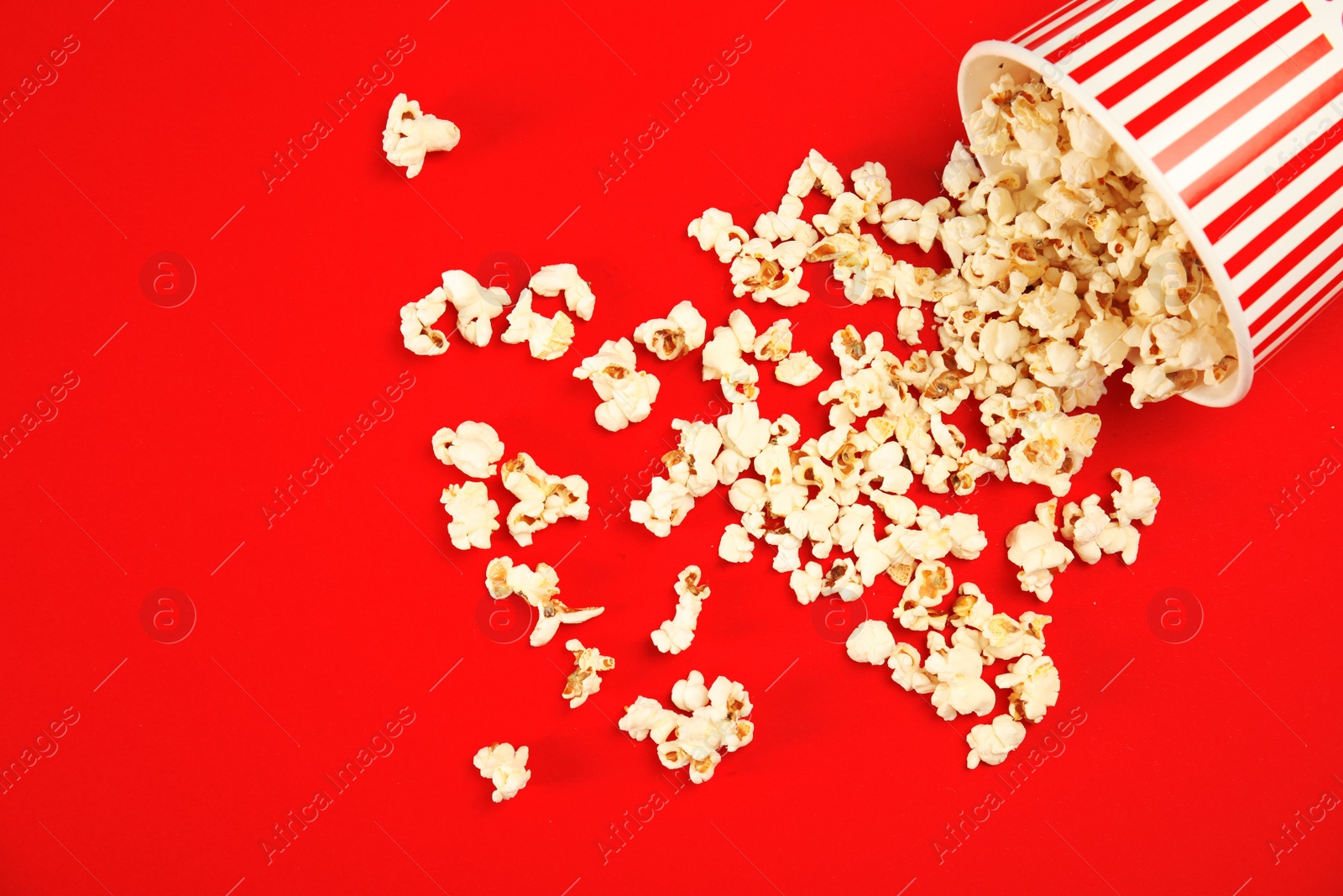 Photo of Paper cup with tasty fresh popcorn on color background, top view