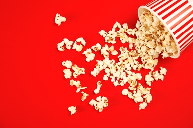 Paper cup with tasty fresh popcorn on color background, top view