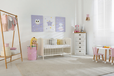 Photo of Baby room interior with cute posters, crib and clothing rack