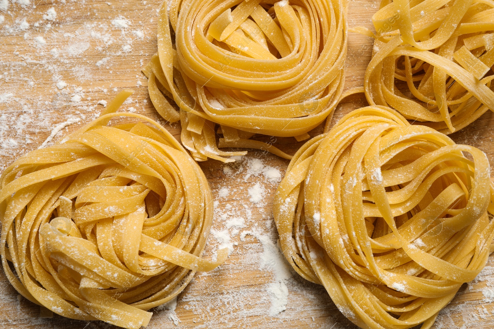 Photo of Tagliatelle pasta on wooden board, flat lay