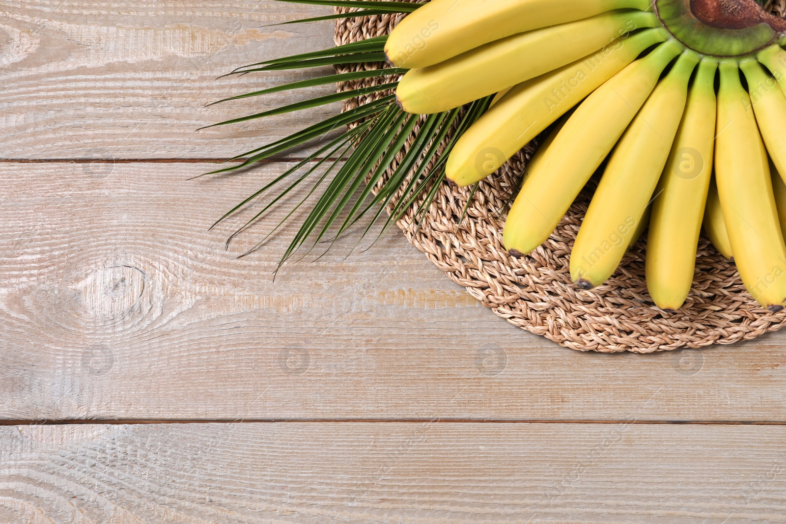 Photo of Bunch of ripe baby bananas on wooden table, above view. Space for text