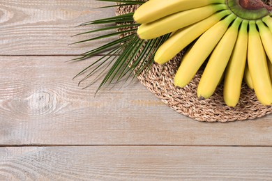 Bunch of ripe baby bananas on wooden table, above view. Space for text