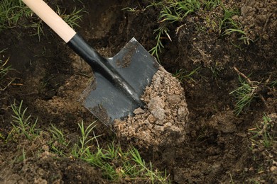 Photo of Digging soil with shovel outdoors, closeup. Gardening tool