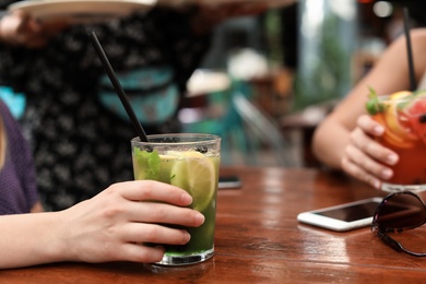 Women with glasses of tasty lemonade at table, closeup