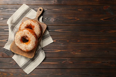 Photo of Delicious fresh bagels with sesame seeds on wooden table, top view. Space for text
