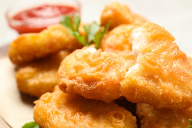 Tasty fried chicken nuggets on light table, closeup