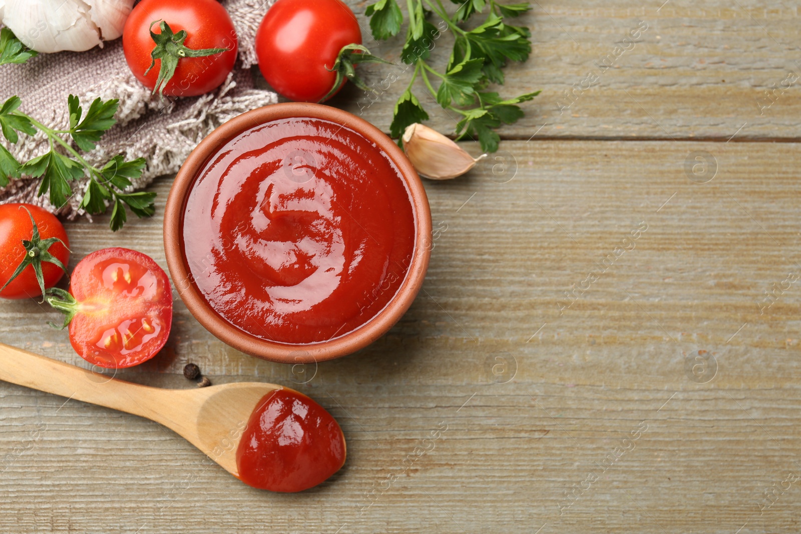 Photo of Tasty ketchup, fresh tomatoes, parsley and spices on wooden table, flat lay. Space for text