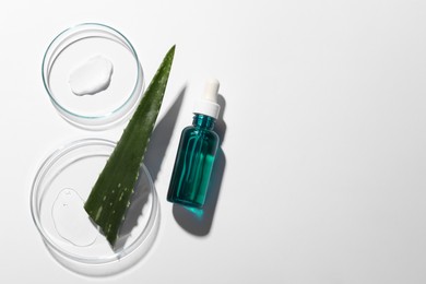 Bottle of cosmetic serum, aloe vera leaf and petri dishes with samples on white background, flat lay. Space for text