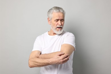 Photo of Arthritis symptoms. Man suffering from pain in elbow on gray background