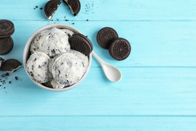 Bowl of ice cream and crumbled chocolate cookies on wooden background, top view with space for text