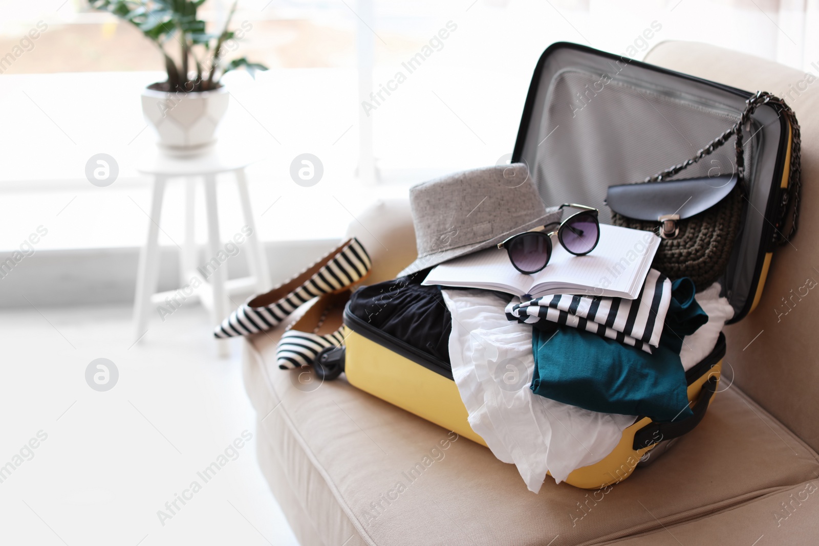 Photo of Open yellow suitcase with different clothes packed for journey at home