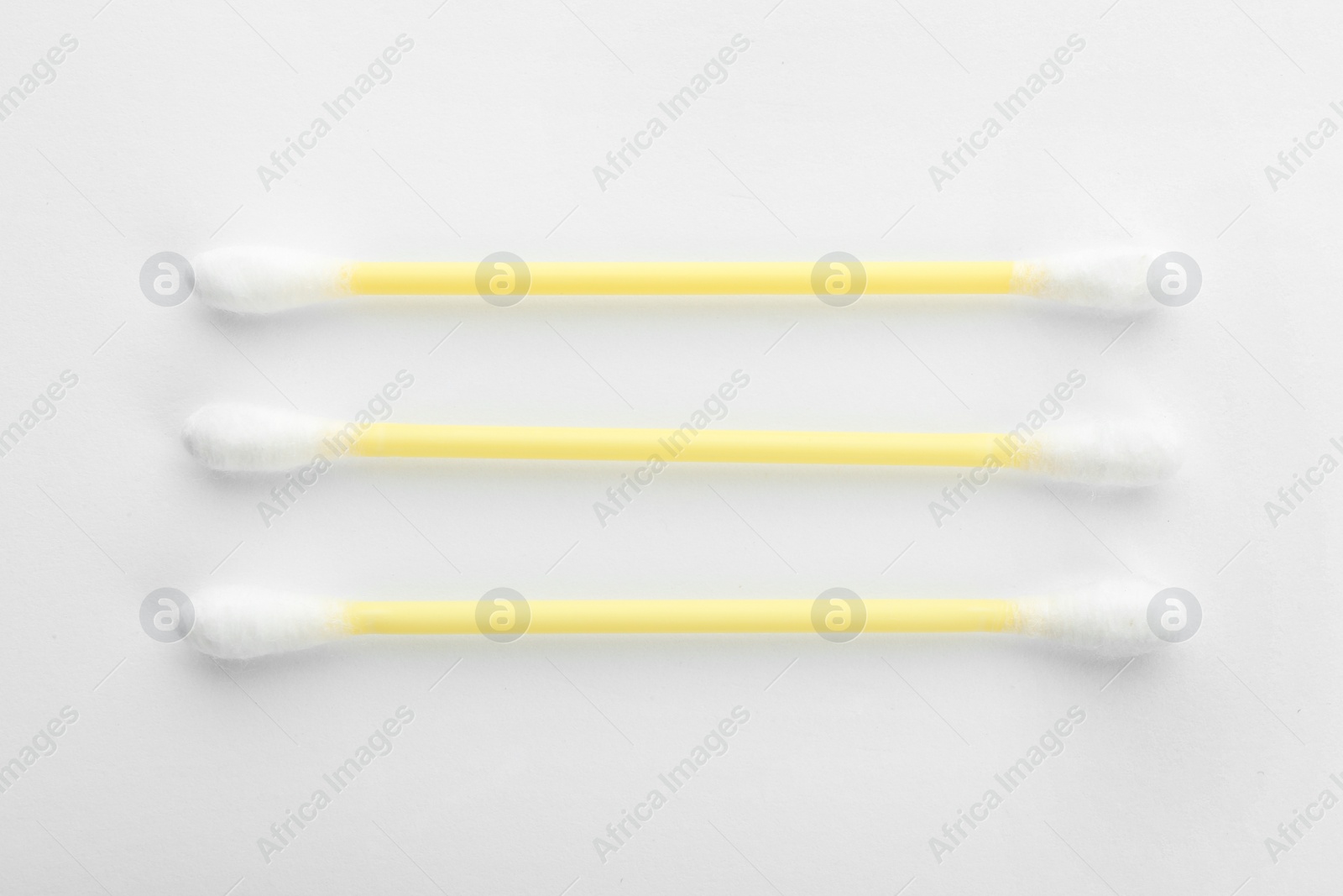 Photo of Yellow plastic cotton swabs on white background, top view