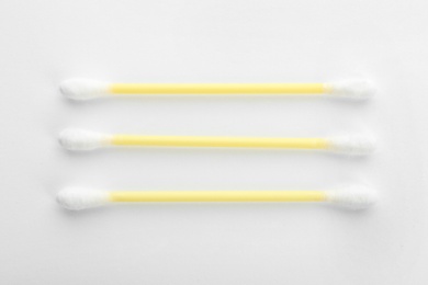 Yellow plastic cotton swabs on white background, top view