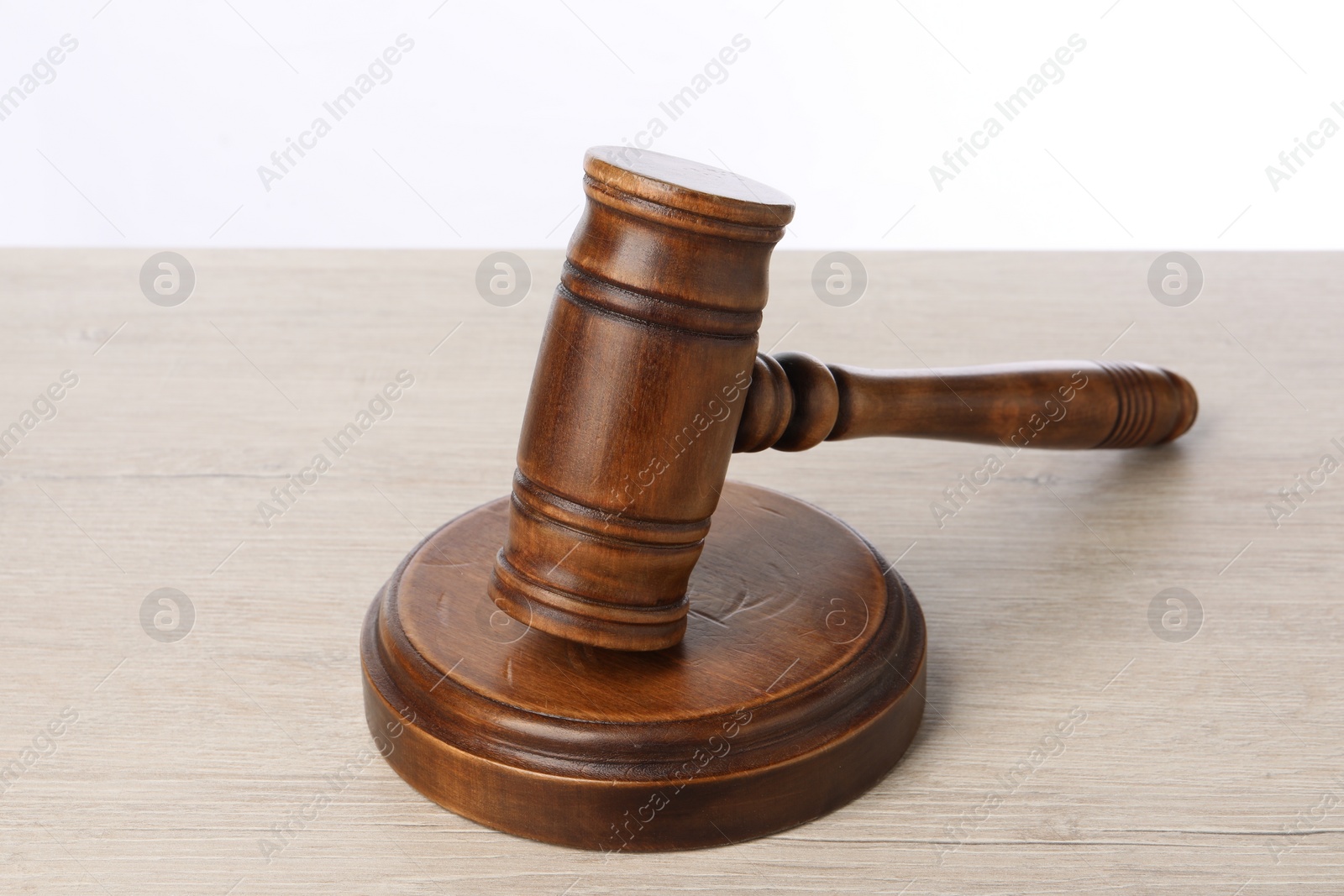 Photo of Wooden gavel on light table against white background