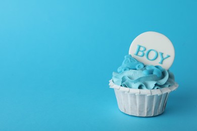 Photo of Baby shower cupcake with Boy topper on light blue background, space for text