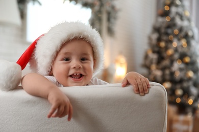 Cute little baby wearing Santa hat at home. Christmas celebration