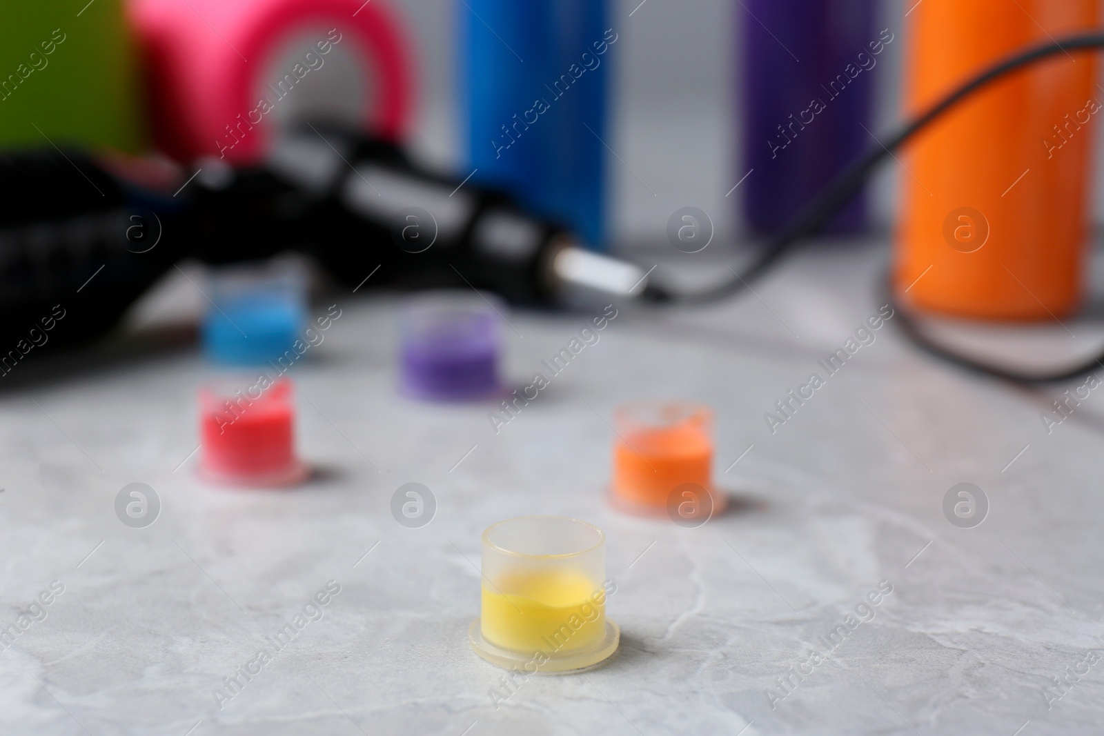 Photo of Tattoo inks and professional tools on light grey table, closeup