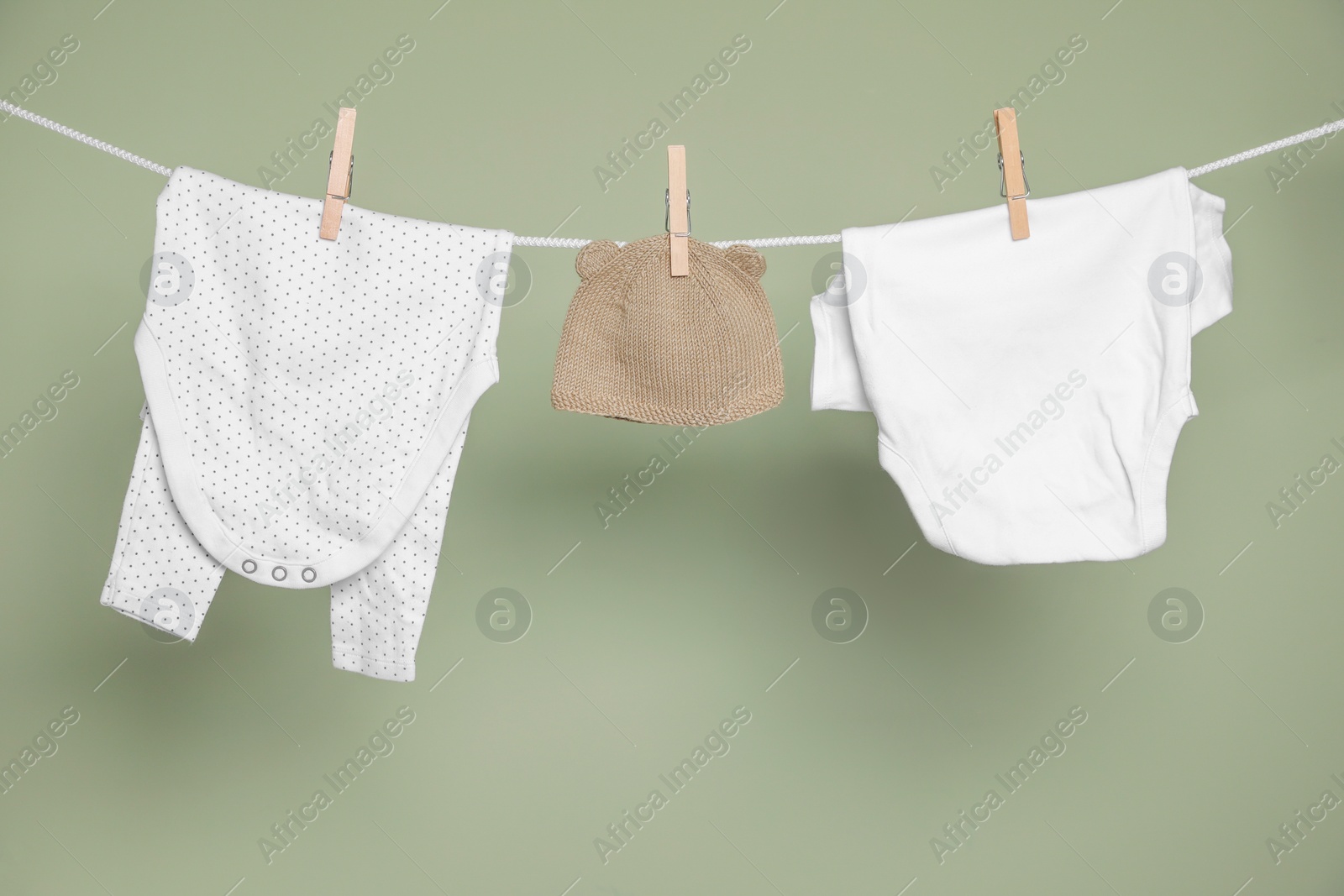 Photo of Cute small baby clothes hanging on washing line against green background