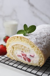 Photo of Delicious sponge cake roll with strawberries and cream on white table, closeup