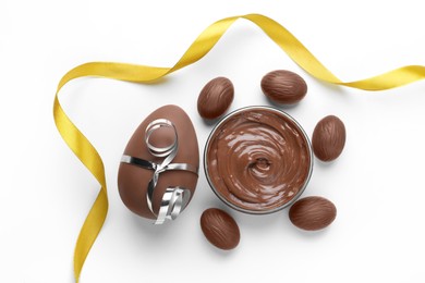 Photo of Delicious chocolate eggs, paste and golden ribbon on white background, flat lay