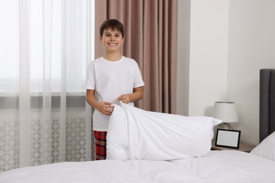 Photo of Boy changing pillowcase in bedroom. Domestic chores