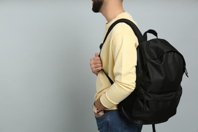 Photo of Young man with stylish backpack on light grey background, closeup. Space for text