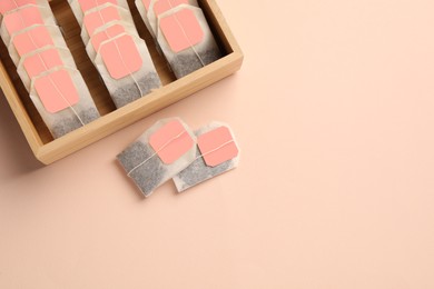 Photo of Many tea bags in wooden box on color background, flat lay. Space for text