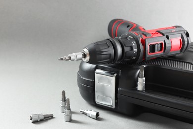 Photo of Electric screwdriver, drill bits and case on grey background. Space for text