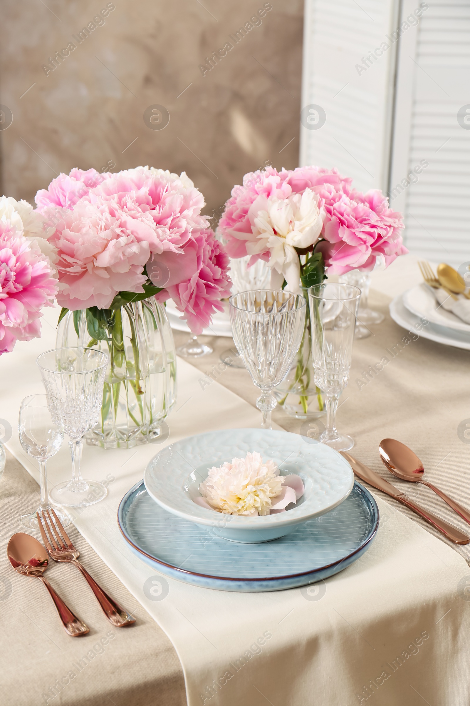 Photo of Stylish table setting with beautiful peonies and golden cutlery indoors