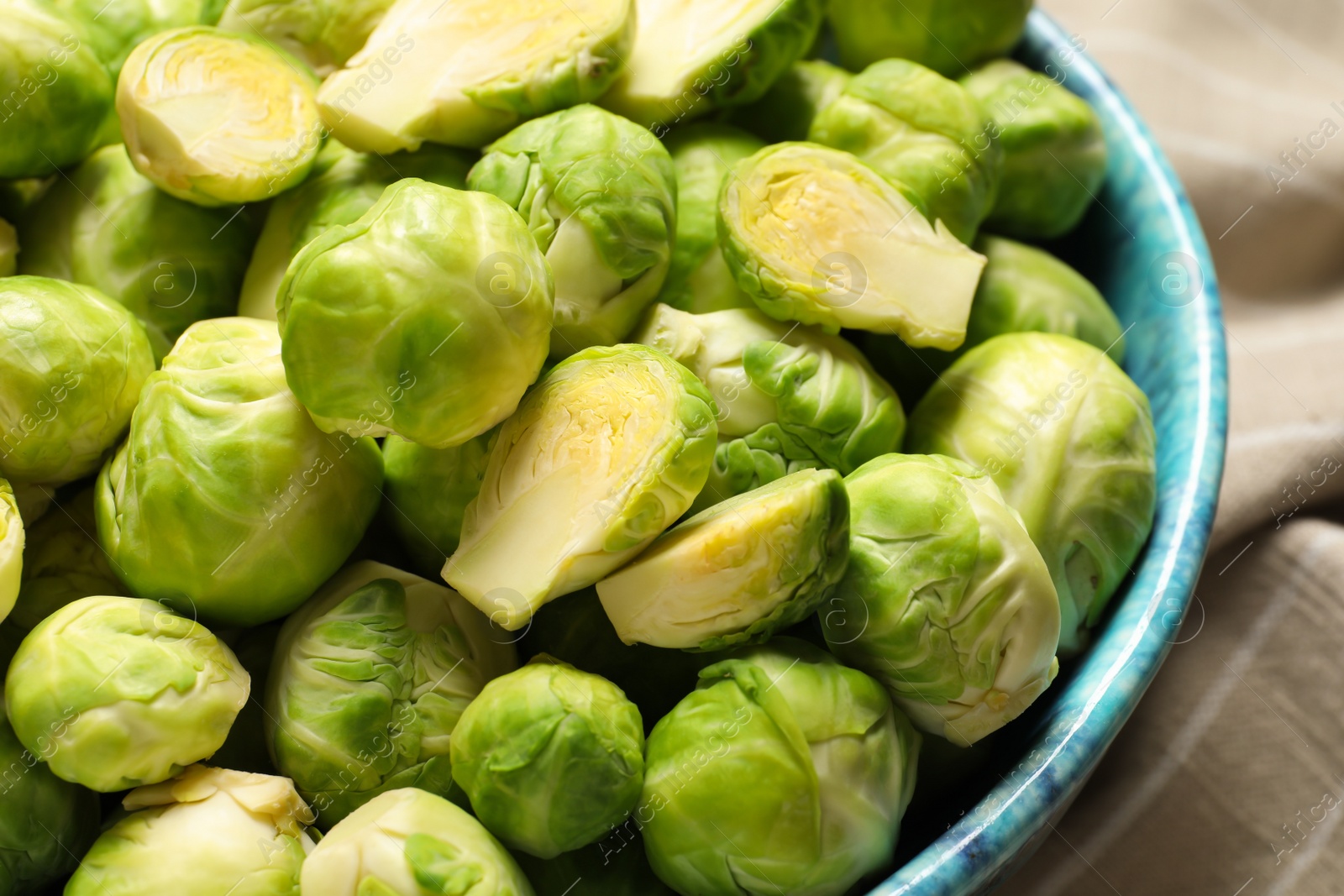 Photo of Bowl with fresh Brussels sprouts on napkin, closeup