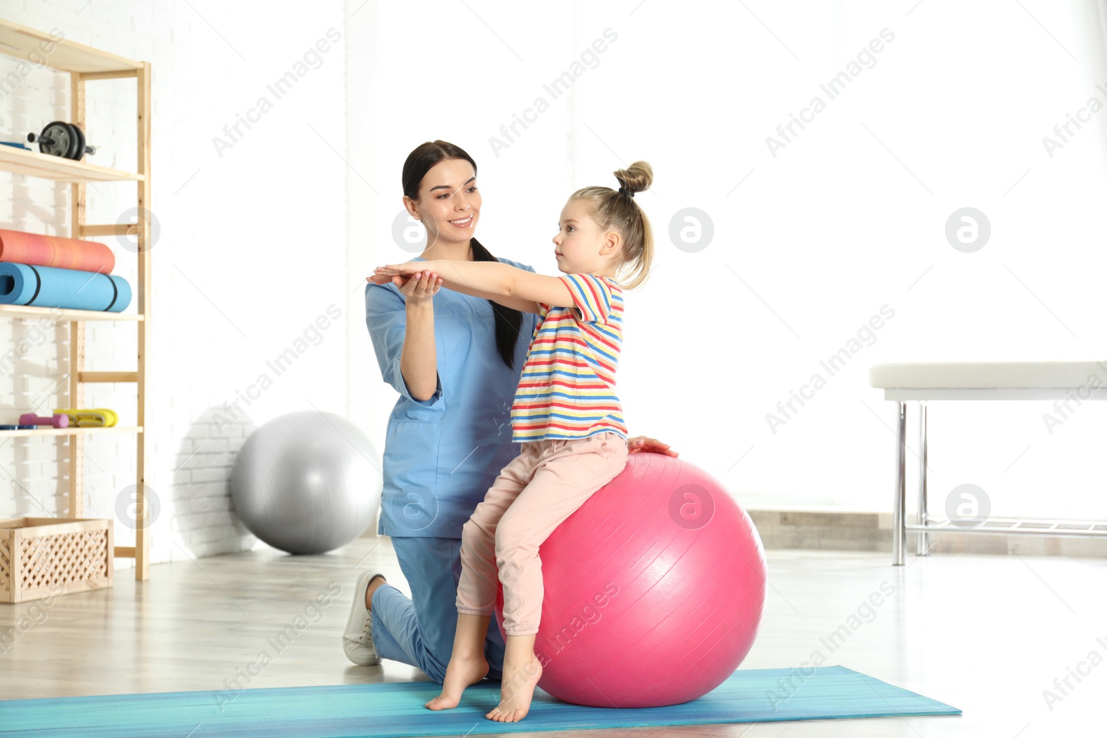 Photo of Orthopedist working with little girl in hospital gym