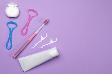 Photo of Flat lay composition with tongue cleaners and teeth care products on violet background, space for text